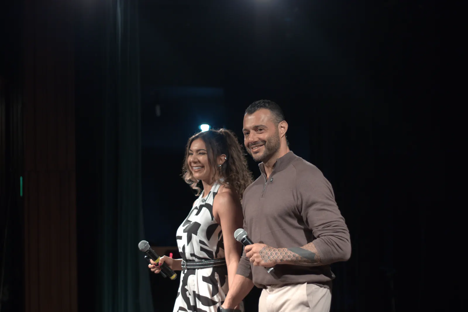Dupla de palestrantes rindo no palco